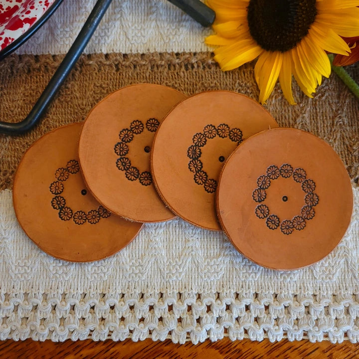 Set of four round leather coasters with floral ring stamped design in medium stain
