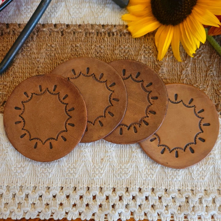 Set of four round leather coasters with a circular scallop and teardrop stamped pattern in medium stain