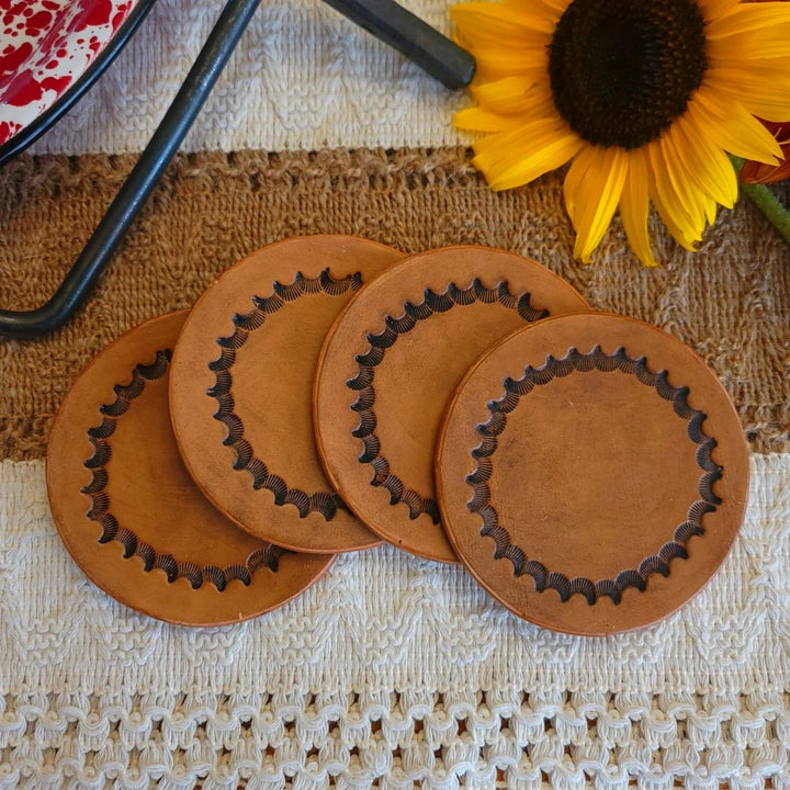 Set of four single-layer leather coasters with inward-facing starburst border design and medium stain finish