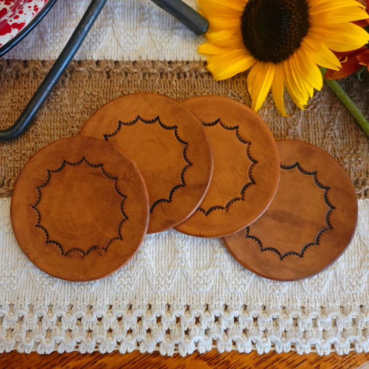 Handmade leather coasters for sale with inward scalloped design, medium brown stain, shown as a full set of four.