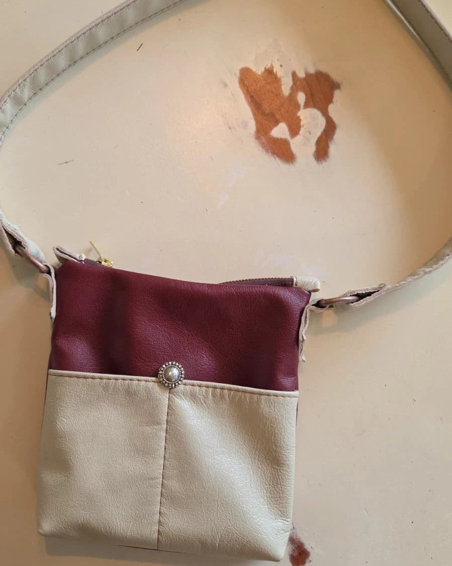 beige and rust leather crossbody purse with a zipper closure
