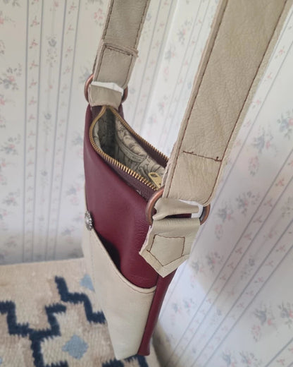 the top view of a beige and rust leather crossbody purse with a zipper closure