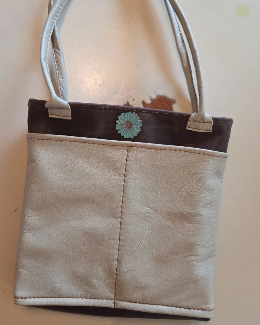 Beige and brown handbag with a blue flower snap closure